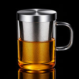 Glass mug with metal mesh infuser and handle, filled with a yellow liquid, on a white background.