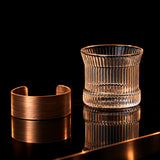 Clear glass with wooden bracelet on a textured surface