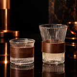 Two glass tumblers with wooden bands on a textured surface