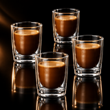 A clear double-walled glass tumbler containing a brown coffee drink, centered on a black reflective surface with a dark studio background.