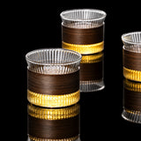 Three glass cups with brown and gold accents on a gray background